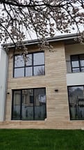 Фасада ЮГ, травертин, минерална мазилка на Baumit, PVC дограма TROCAL с троен стъклопакет